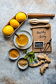 Ingredients for a healthy recipe laid out on a rustic kitchen countertop, featuring lemons, herbs, and spices