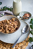 A nutritious bowl of granola with a bottle of fresh milk and eucalyptus leaves, ready for a healthy start to the day