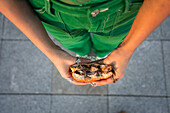 Overhead view of a person holding a half-eaten burger in an urban setting, possibly near Madrid's Four Towers Business Area.