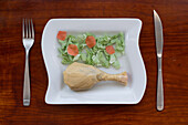 Konzeptbild von oben, das eine Mahlzeit aus Plastiktüten in Form von Lebensmitteln zeigt, die auf einem weißen Keramikteller serviert werden, mit einer echten Gabel und einem Messer auf jeder Seite.