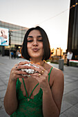 A stylish woman enjoys the sunset in Madrid with the city's iconic Four Towers in the background, showcasing urban Spanish life.