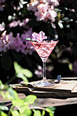 Rosa Gin-Cocktail mit Blüte und Eiswürfeln