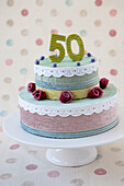 Zweistöckige DIY-Torte aus verschiedenen Stoffen mit "50" und Rosenverzierung