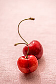 Two cherries on pink background