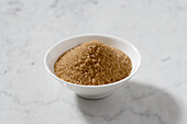 Bowl of brown cane sugar on a marble plate