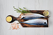 Raw mackerel on a wooden board with lemon