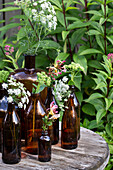 Brown glass bottles with wildflowers on a wooden table in the garden