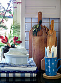 Pile of tea towels, chopping boards and cup with candles in country-style kitchen