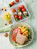 Sandwich with omelette and vegetables, served with grapes and snack skewers