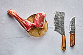 Raw venison leg on a chopping block with butcher's cleavers