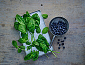 Spinach leaves and blueberries on a wooden background