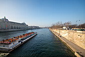 Bateau mouche sightseeing cruise glides on the Seine River by Orsay Museum, in Paris.