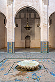 Tranquil courtyard featuring a traditional fountain with intricate tile work in Fez, Morocco.
