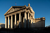 The setting sun casts shadows on the Panthéons grand neoclassical façade in Paris.