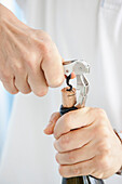 Man's Hands Opening Wine Bottle with Corkscrew