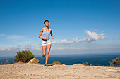 Woman Running along Cliff by Ocean