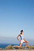 Woman Stretching against Ocean and Blue Sky