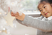 Nahaufnahme eines jungen Mädchens beim Schmücken des Weihnachtsbaums