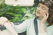Nahaufnahme eines Teenager-Mädchens, das während des Autofahrens mit dem Smartphone telefoniert