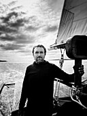 Half-length portrait of bearded mid-adult man standing on sailboat