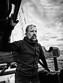 Half-length portrait of contemplative mid-adult man standing on sailboat