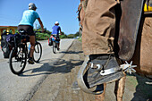 Kuba,östliche Region,2 Radtouristen fahren vor einem Mann auf einem Pferd vorbei,nur sein Bein und seine Sporen
