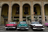 Kuba,La Havanna,Paseo de Marti,3 alte rote und pinke amerikanische Autos aus den 50er Jahren parken und warten auf Touristen