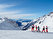 Austria,Tyrol,Sankt Anton am Arlberg ski resort,a group of skiers in front of a superb panorama of snowy mountains