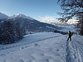 Austria,Tyrol,a man carrying a yellow backpack is hiking in the fresh snow in front of the Stubai Alps