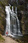 Österreich,Steiermark,ENNSTAL Alpen, ein Mann steht vor einem hohen Wasserfall in der Wasserlochklamm