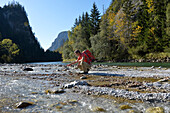 Austria,Styria,ENNSTAL Alps, Geseause National Park,a man squatting observes the ENNS river