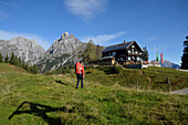 Österreich,Steiermark,ENNSTAL Alpen, ein einsamer Mann mit rotem Rucksack geht zur Mödlinger Hütte oberhalb der kleinen Stadt Admont, ein hohes Holzkreuz steht vor dem Hütteneingang