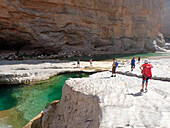 Sultanat Oman,AS Sharqiyah Region,Wadi Bani Khalid Canyon,eine Gruppe europäischer Touristen wandert durch einen Canyon, in dem klares grünes Wasser fließt