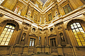 Paris. 1. Bezirk. Louvre-Museum bei Nacht. Quadratischer Innenhof. Fassade des Uhrenpavillons. Architektonisches Detail. Statue.