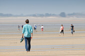Frankreich. La Manche. Hauteville sur Mer bei Ebbe. Frühjahrsschulferien. Touristen, die am Strand spazieren gehen.