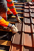 Worker installing tiles on a roof