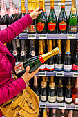 Blonde Frau beim Einkaufen im Supermarkt während einer Weinmesse. Champagner Moët et Chandon