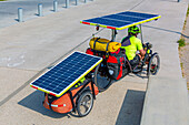 Reisende mit Dreirad mit Anhänger, ausgestattet mit Solarzellen