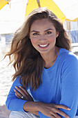 Woman in blue jumper sitting on the beach