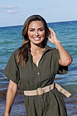 Frau in khakifarbenem Kleid am Strand