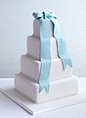 Four-tier wedding cake with blue fondant ribbon