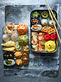 Bento box with sushi, dumplings and vegetables
