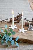 Burning candles in star-shaped holders with eucalyptus branches on a wooden board