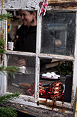 Weihnachtlich dekoriertes Fenster mit lachender Frau im Hintergrund