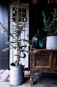 Kleiner Weihnachtsbaum im Zinktopf neben antikem Holztisch