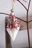 Selbstgemachter Origami-Anhänger mit rotem Blattmuster am Ast