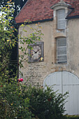 Steinhaus mit Turmuhr und Rosen im Vordergrund