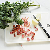 Kale with sausage, bacon and onion on a chopping board