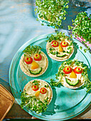 Rice cakes with hummus, cress and vegetable faces