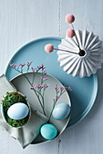 Minimalist Easter table setting with coloured eggs and dried flowers